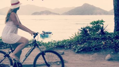 Amanda passeia de bicicleta pela orla de praia em Seychelles.