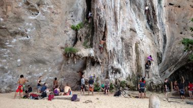 Turistas escalando paredão rochoso em Railay Beach, Krabi, Tailândia.