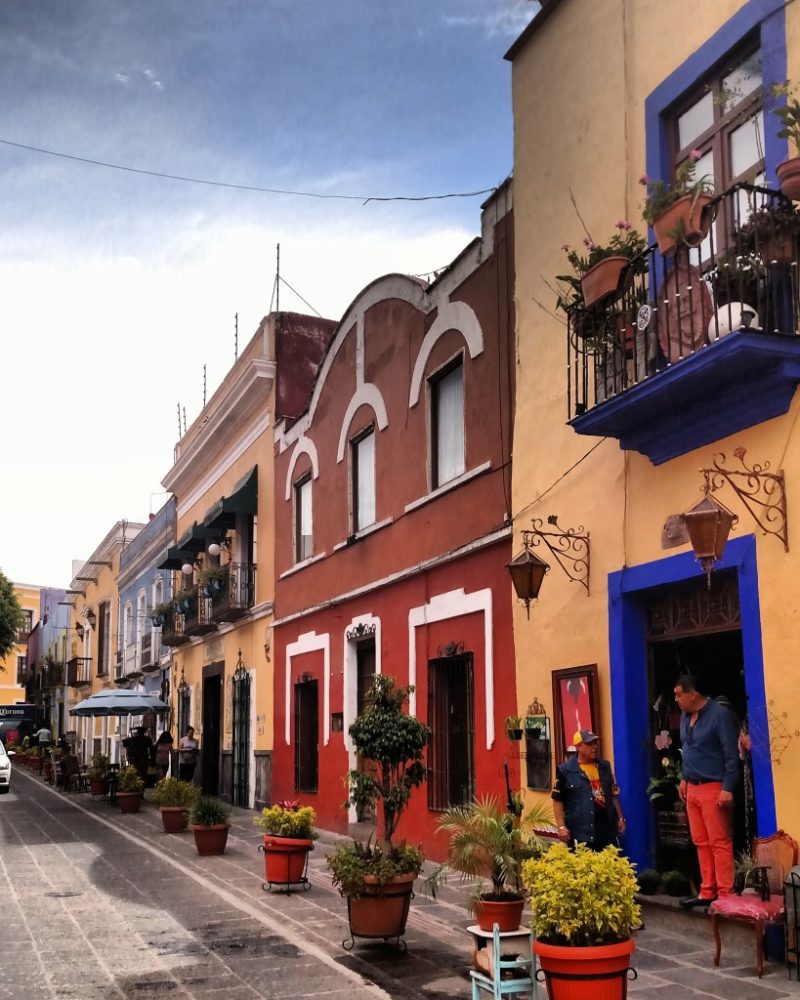 Rua cercada por prédios antigos de fachadas coloridas em Puebla, no México.