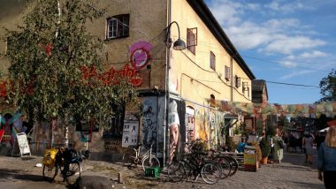 Esquina de prédio cercado por um estacionamento de bicicletas e barracas de venda em Christianshavn, Copenhagen, Dinamarca.