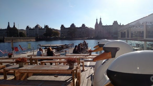 Pier perto de ponte em Copenhagen, com mesas de cafés e pedalinhos como opção de passeio.