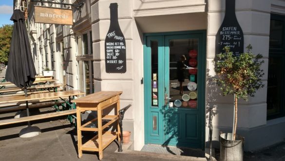 Entrada de café na Rua Jægersborggade, com porta colorida que se destaca com a parede de cor clara.