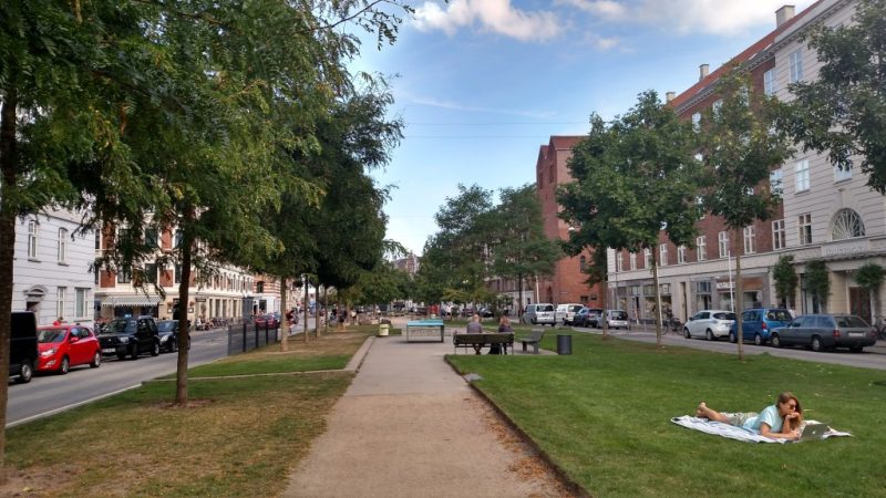 Espaço com gramado, bancos e mesas entre ruas deSonder Boulevard, em Copenhagen, Dinamarca.