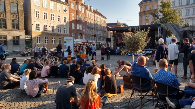 Público prestigiando apresentação artística em praça de Copenhague, na Dinamarca.