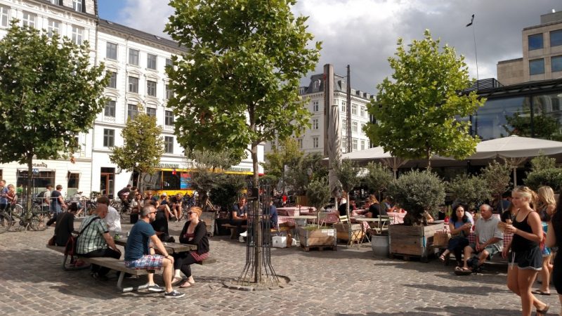 Mesas ao ar livre, com calçadão arborizado, no Torvehallerne Market, no centro de Copenhaga, Dinamarca.