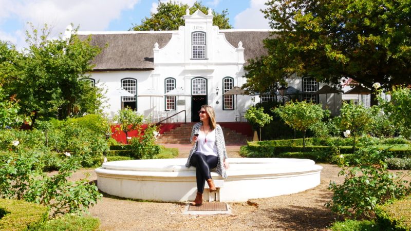 Com taça de vinho na mão, Amanda admira a paisagem em vinícola da região Franchhoek, na África do Sul.