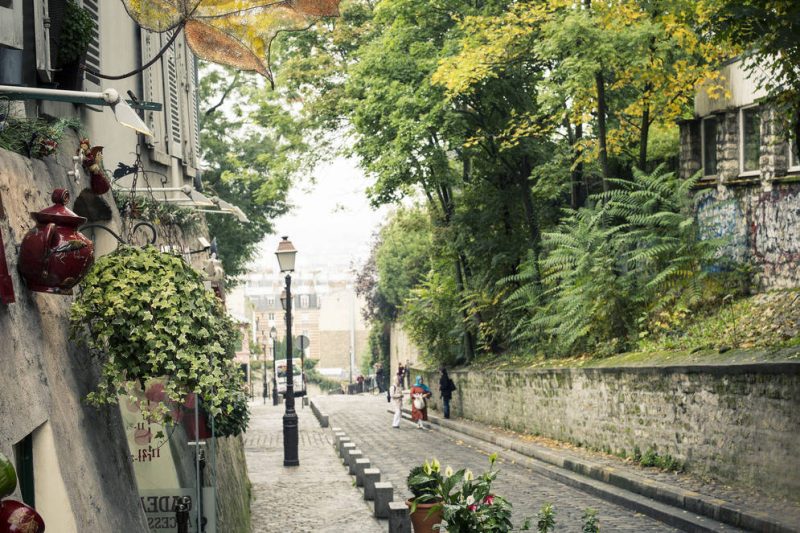 Pequena rua de pedestres arborizada e com plantas, no bairro Montmartre, em Paris, na França.