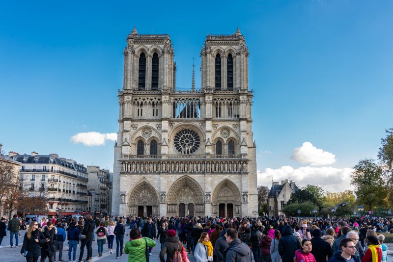 Pedestres transitando por Paris, passando em frente a Catedral de Notre Dame.