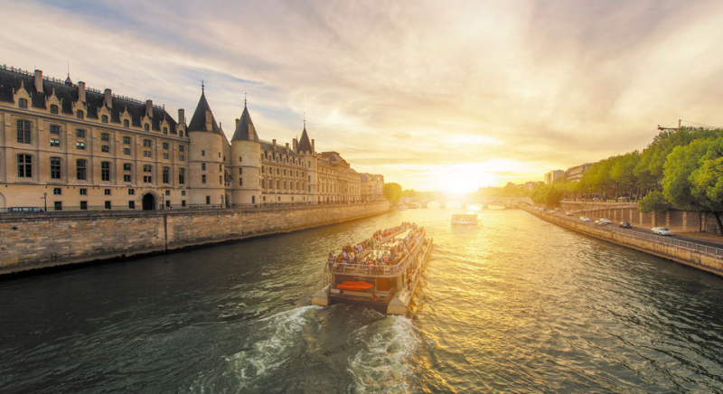 Entardecer no rio Sena, com cruzeiros passando pelas construções históricas de Paris.