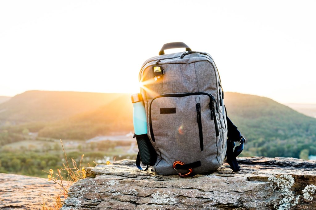 Mochila para trilhar montanhas sobre uma pedra e com uma montanha ao fundo